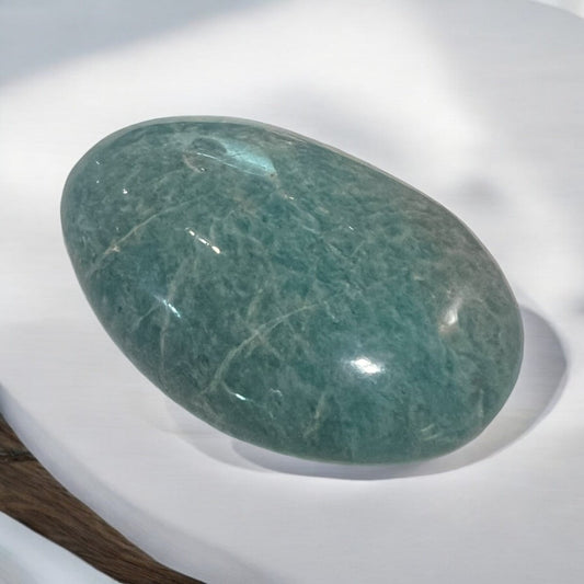 A beautifully polished Amazonite palm stone, ergonomically shaped for easy holding, showcasing calming blue-green colours and smooth textures that promote relaxation and emotional stability.