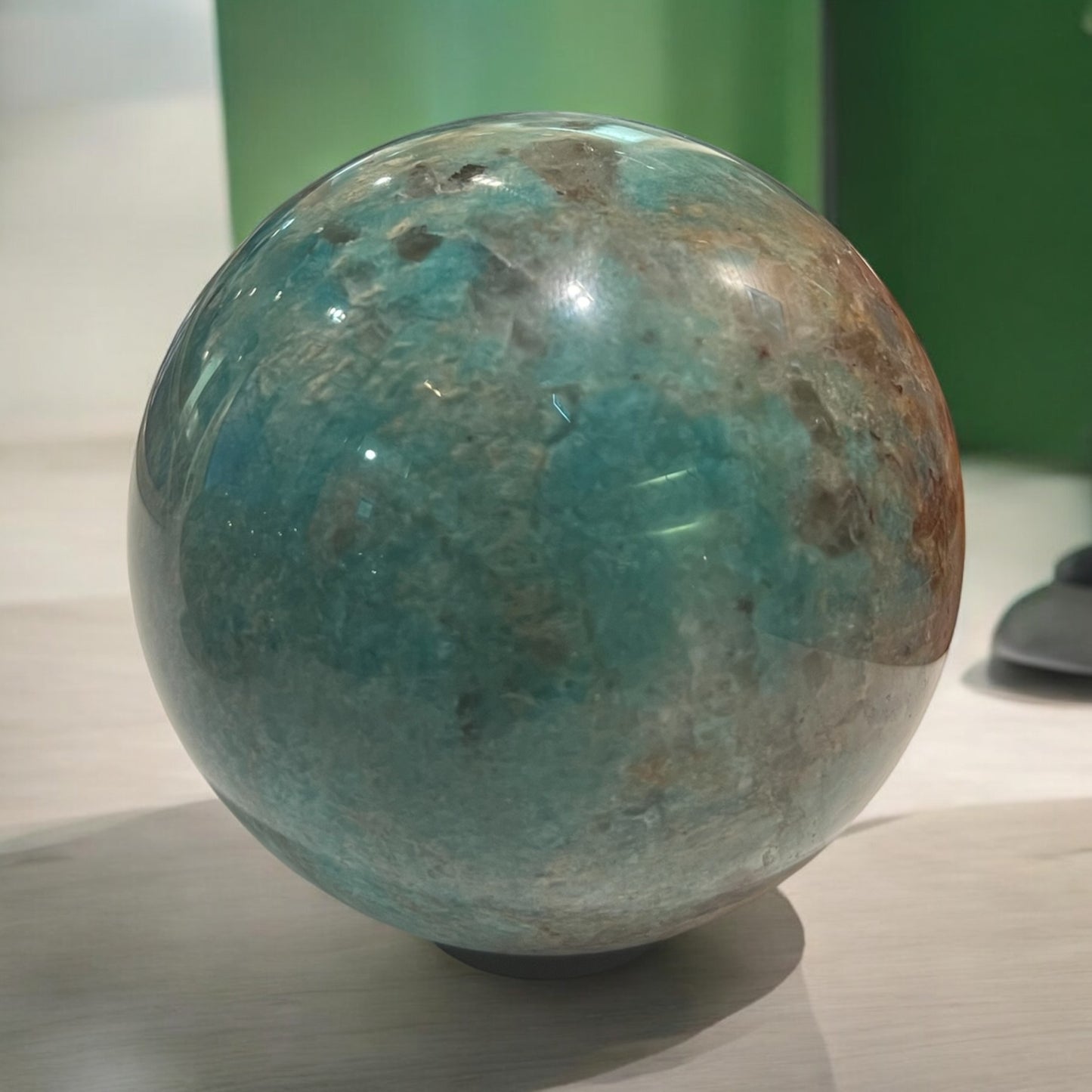 A polished crystal sphere, showcasing vibrant blue-green colours and unique natural patterns, representing unity and clarity while promoting positive energy