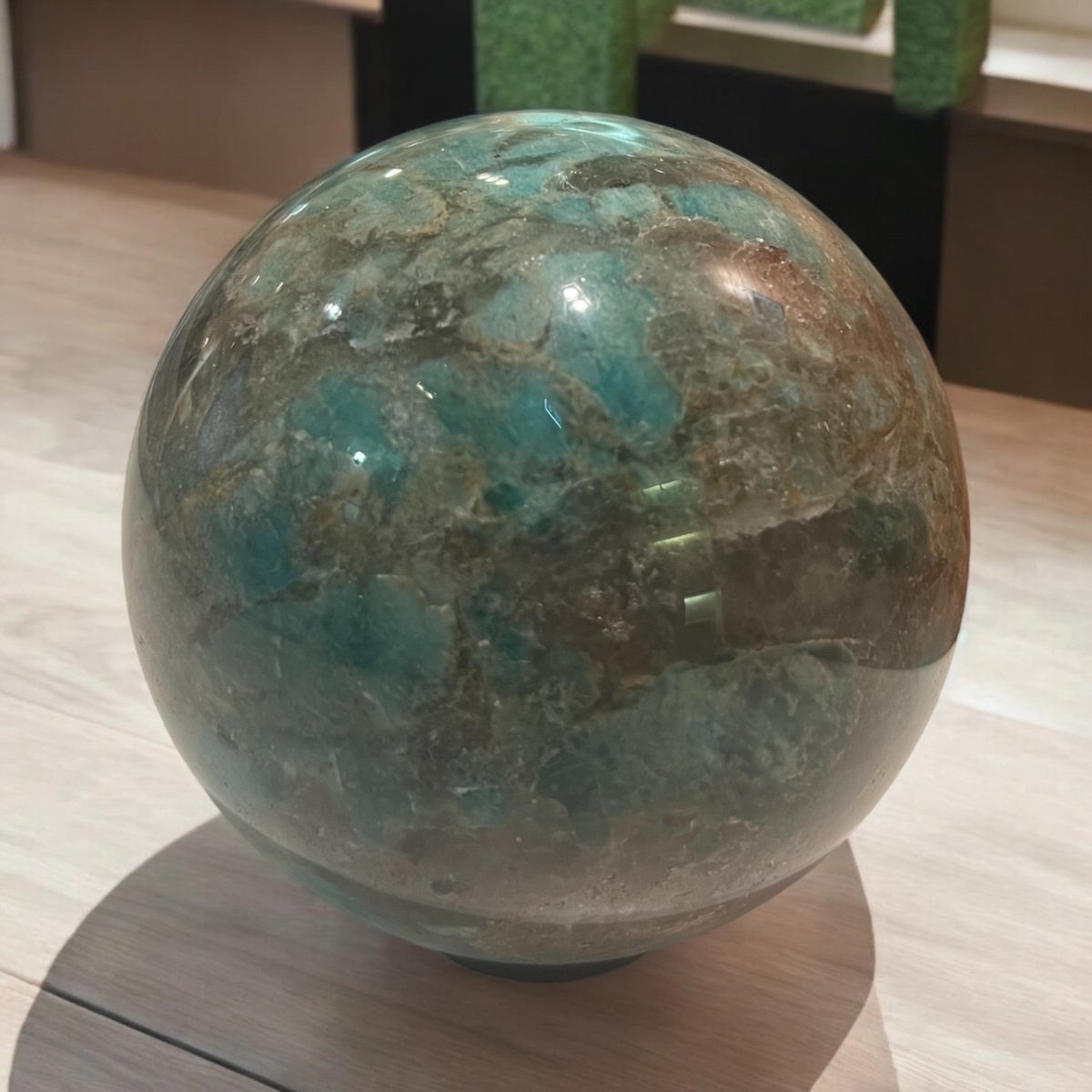 A polished crystal sphere, showcasing vibrant blue-green colours and unique natural patterns, representing unity and clarity while promoting positive energy