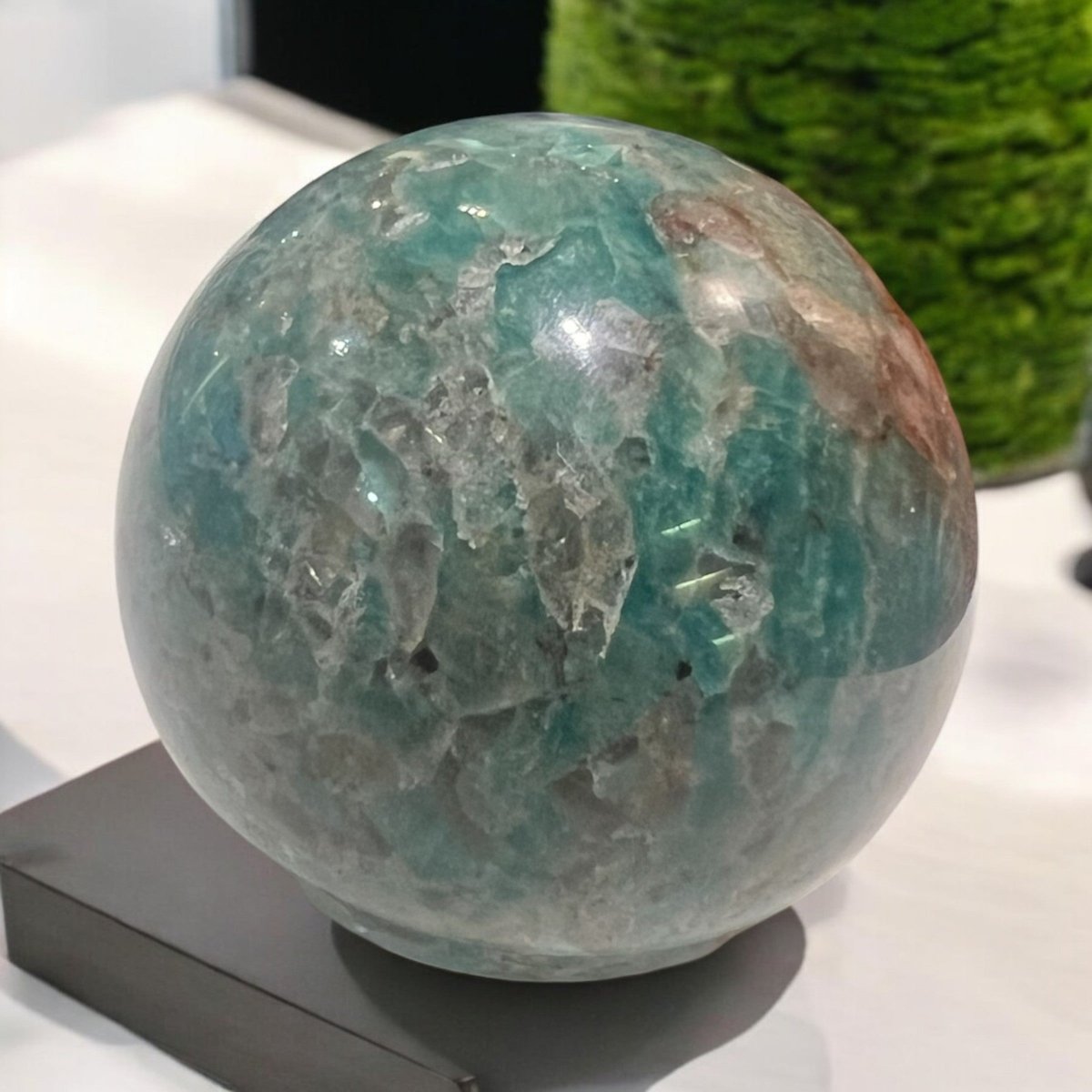 A polished crystal sphere, showcasing vibrant blue-green colours and unique natural patterns, representing unity and clarity while promoting positive energy